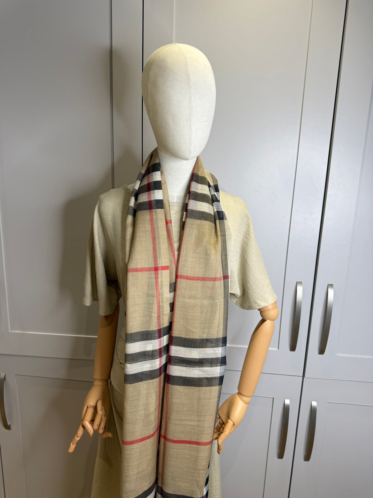 Mannequin wearing a Burberry silk and wool scarf against 
