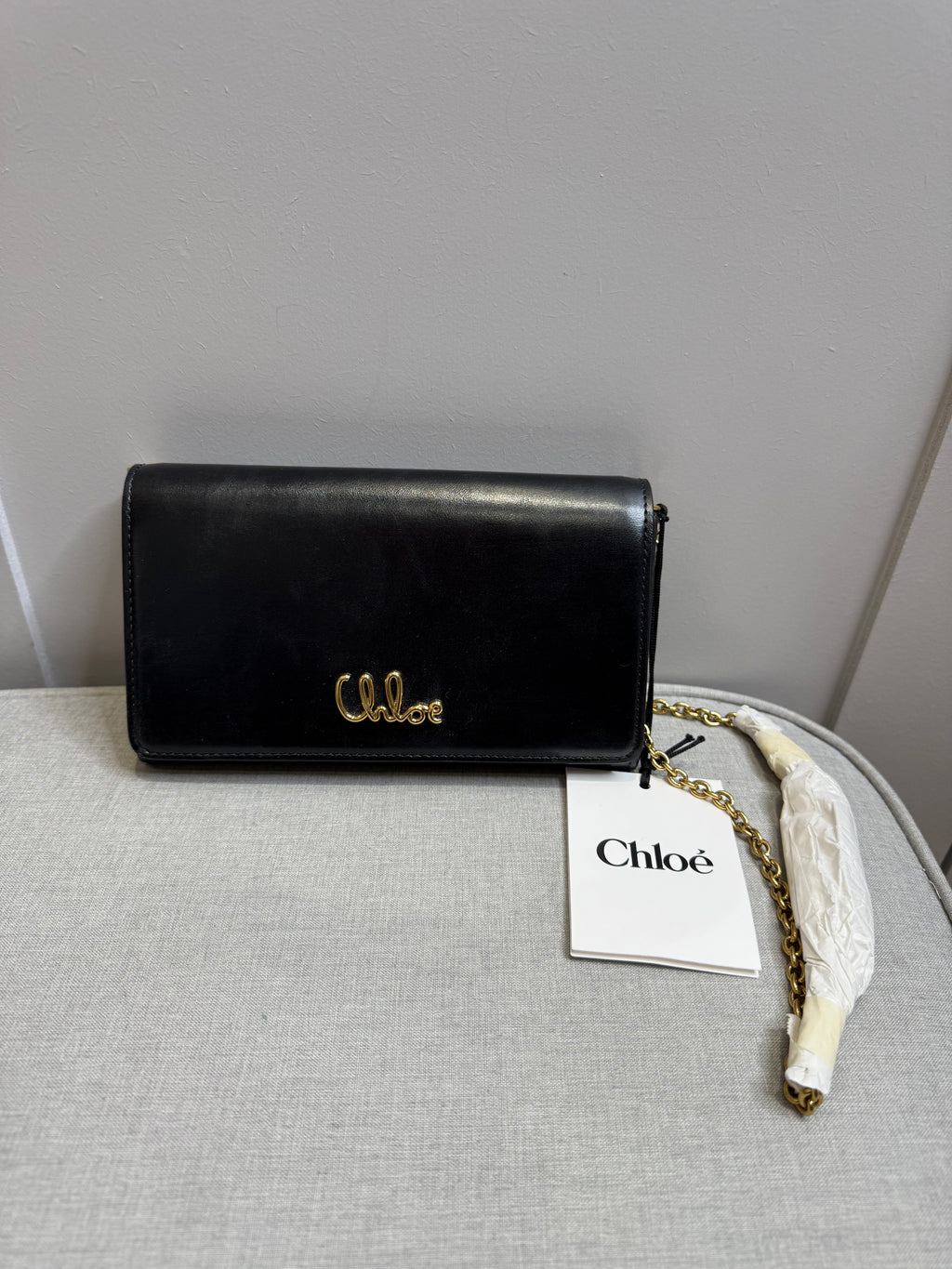 Brand new authentic Chloé black leather wallet on chain (WOC) bag with gold-tone logo and chain shoulder strap.