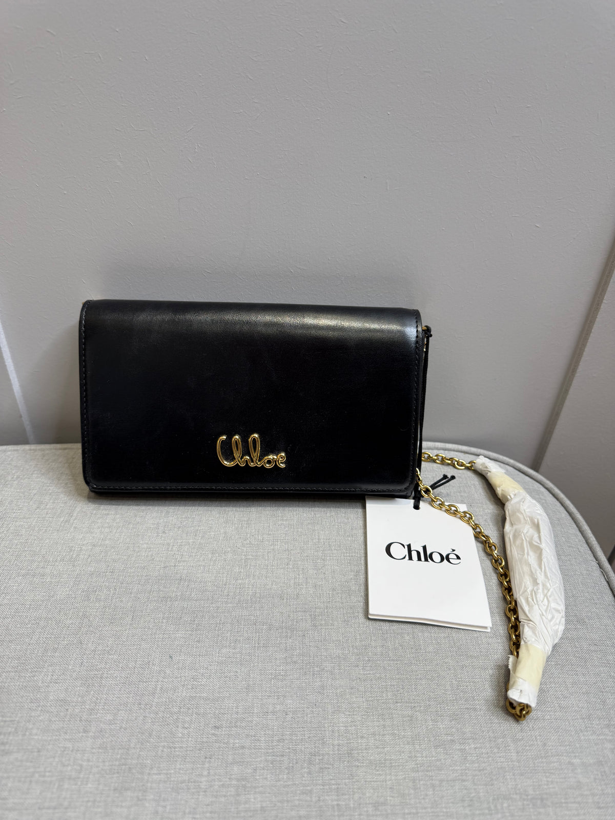 Brand new authentic Chloé black leather wallet on chain (WOC) bag with gold-tone logo and chain shoulder strap.