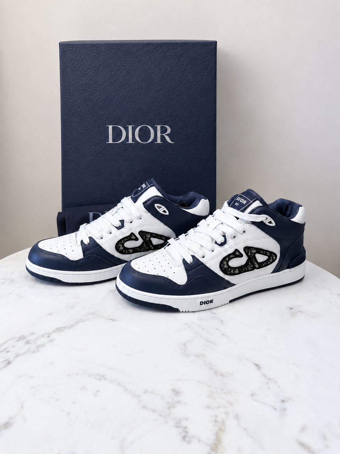Dior B57 Mid Oblique Blue sneakers crafted in white and navy blue calfskin with the signature Dior Oblique jacquard CD logo on the side.