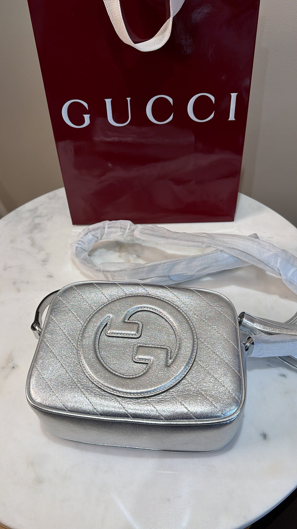     Close-up of the interlocking G leather logo on silver Gucci Blondie bag.