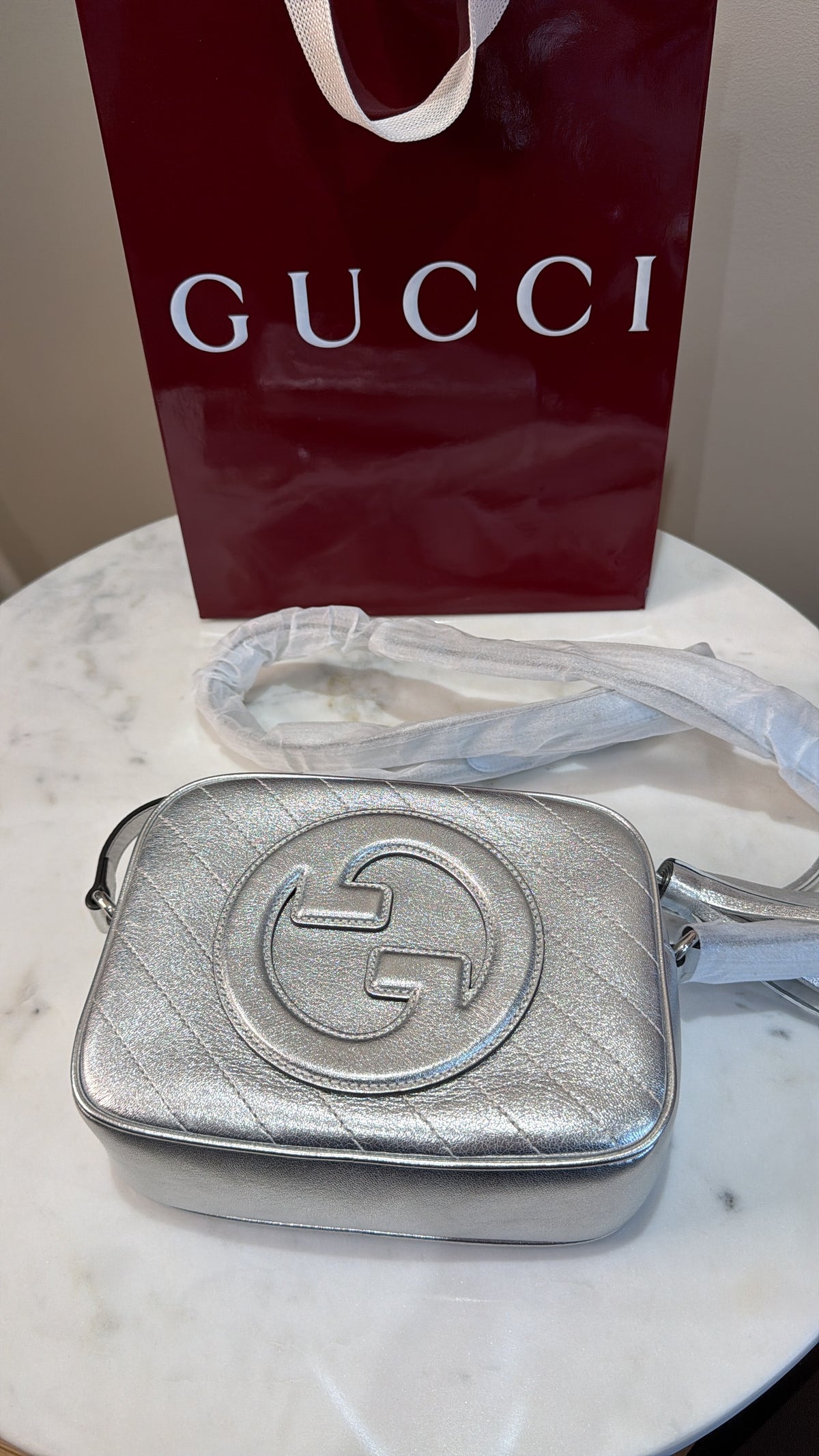     Close-up of the interlocking G leather logo on silver Gucci Blondie bag.
