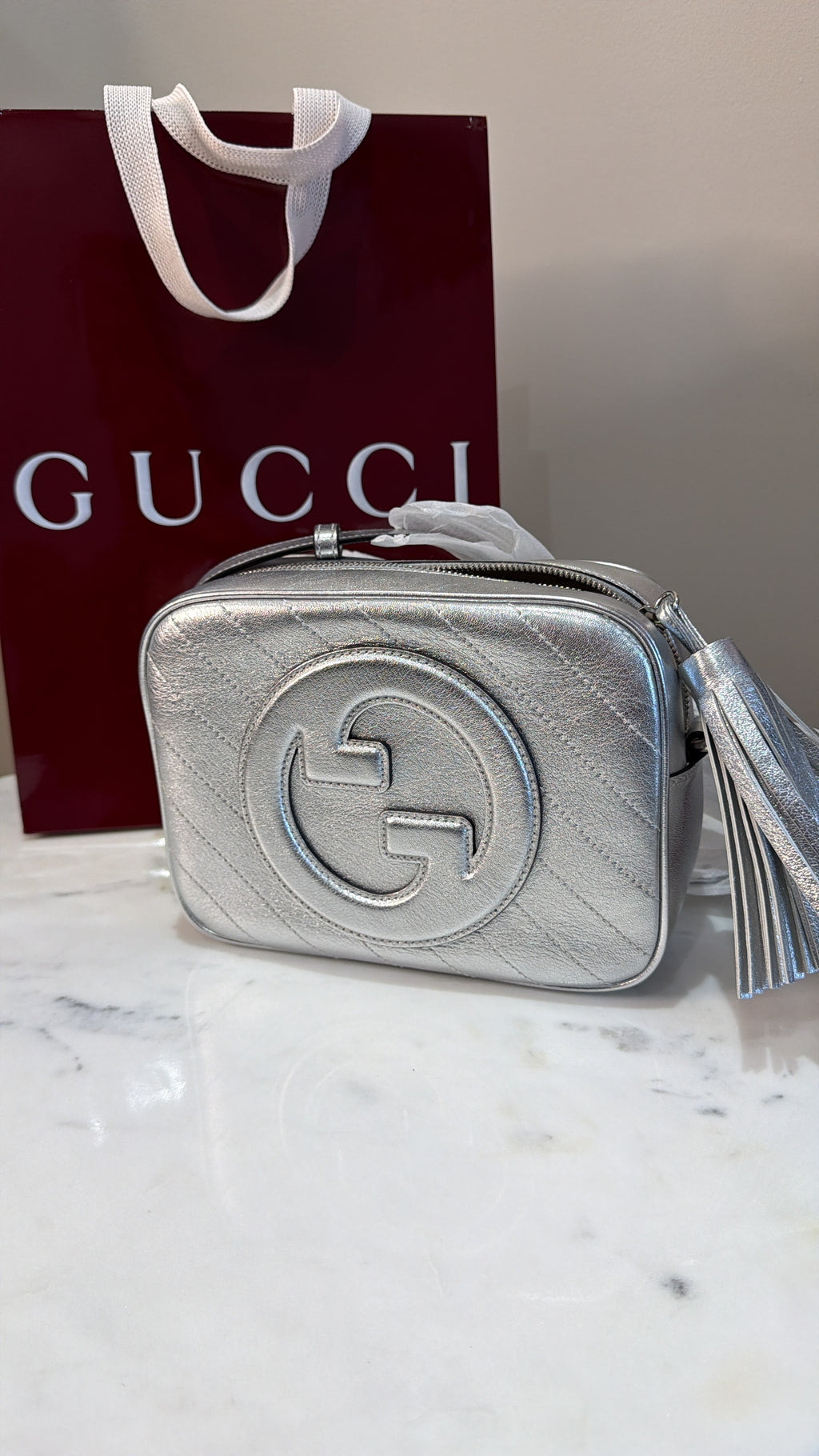     Side view of silver Gucci Blondie bag showing the leather strap attachment.