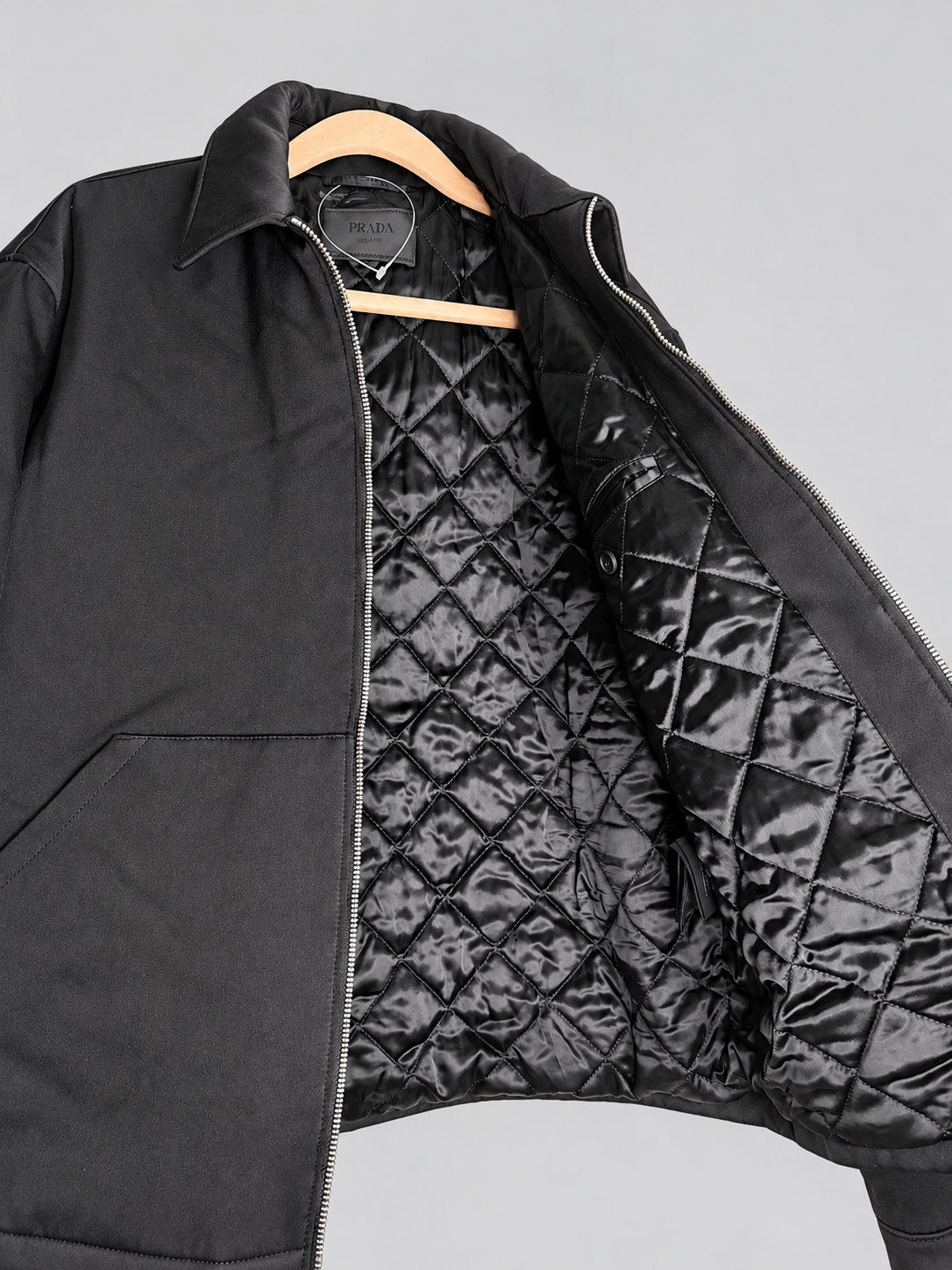 A black zip-up Prada jacket with a quilted black interior lining.